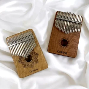 Two Goldesi kalimbas on white fabric background, one with decorative engraving and the other plain.