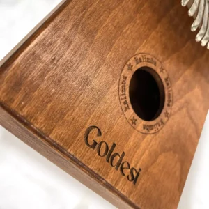 Close-up of a mahogany Goldesi Kalimba showing the wood grain and soundhole design.