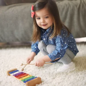 Cute little girl playing Goldesi’s colorful xylophone and smiling in a peaceful home setting